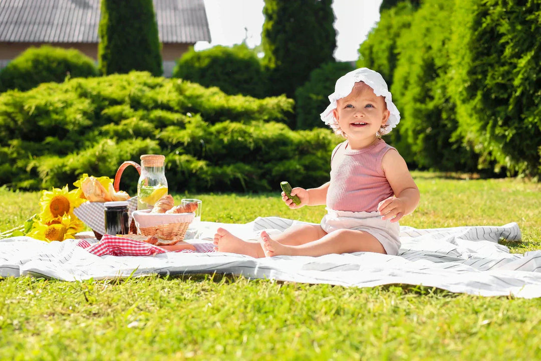 Baby enjoying a summer meal on a picnic blanket