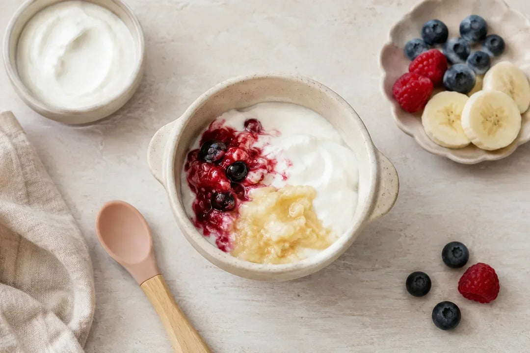 Plain full-fat baby yogurt served with mashed fruit for a baby starting solids